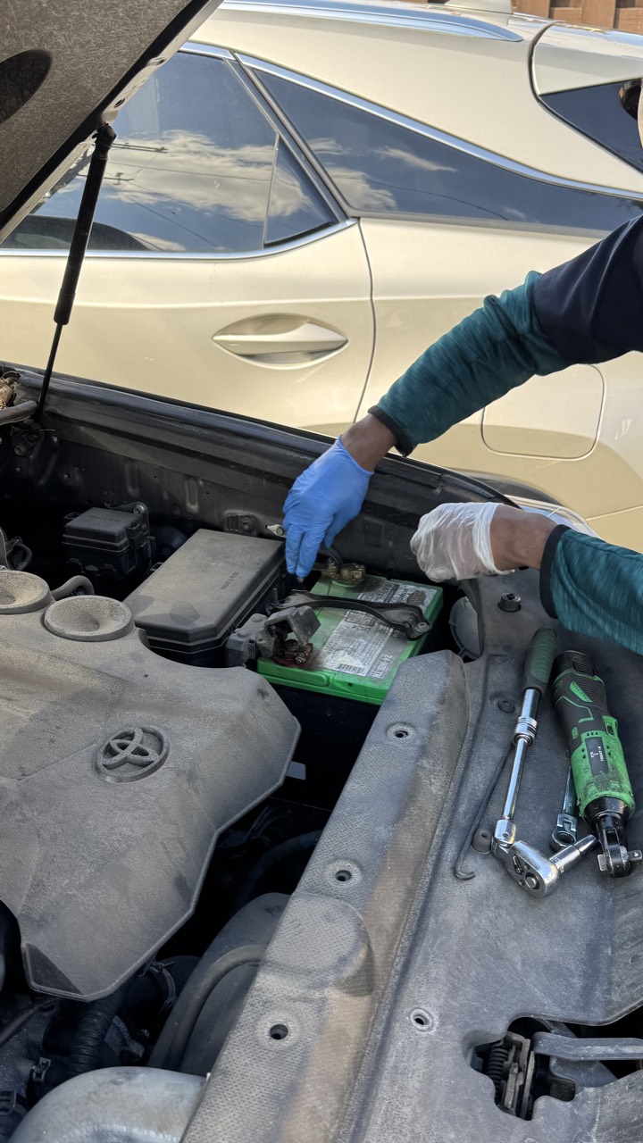 Mechanic disconnecting the old battery under the hood